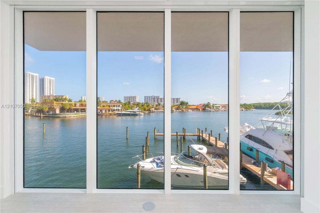 Floor-to-ceiling picture windows featuring a multi-panel design and white frames, overlooking a private dock on the waterway