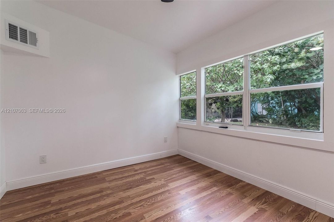 Interior room featuring wood-finish flooring, white walls, and a multi-pane window configuration