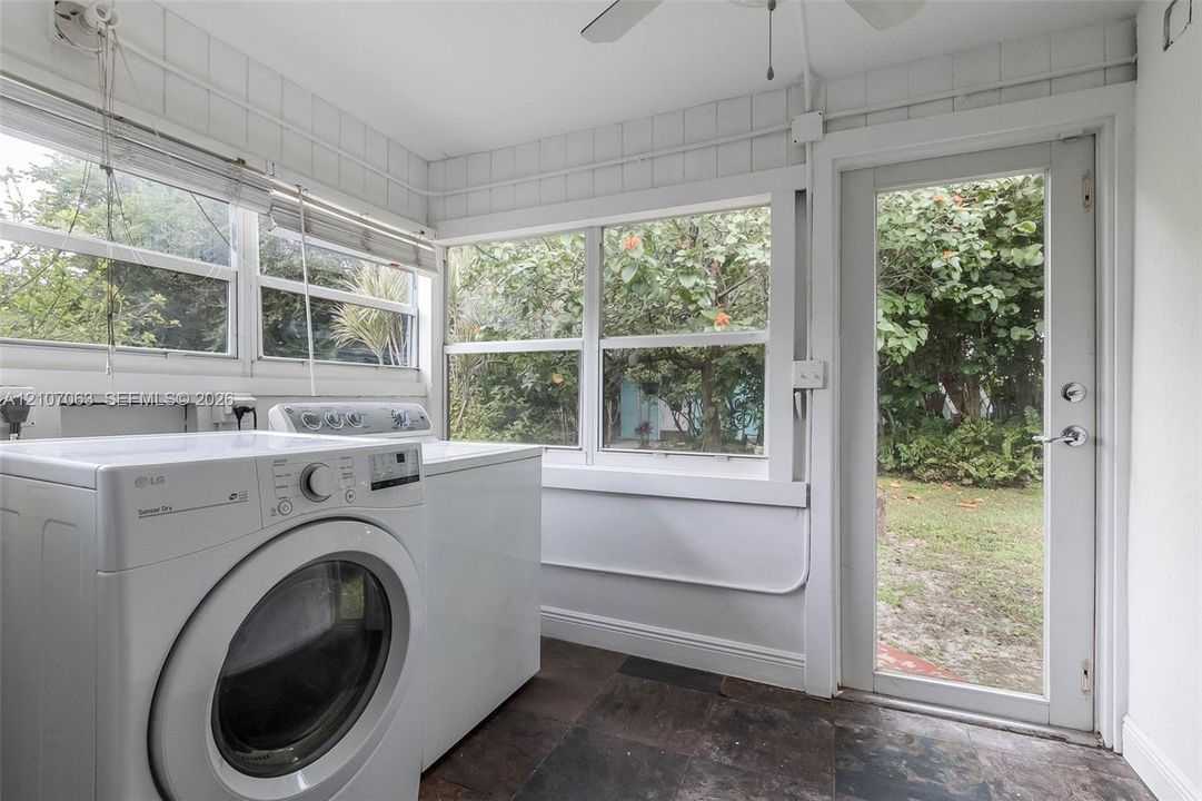 Utility room featuring large-format dark tile flooring, multi-pane windows, and a glass-panel exterior door