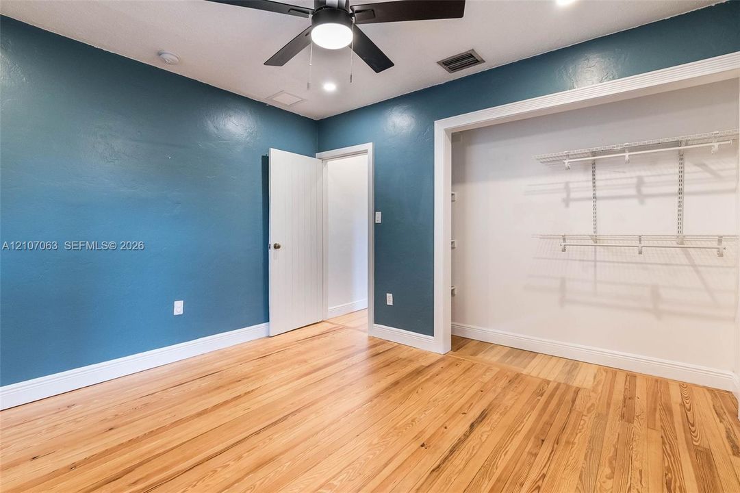 Room featuring wood-finish flooring, a ceiling fan with integrated lighting, recessed ceiling lighting, and a closet with built-in wire shelving
