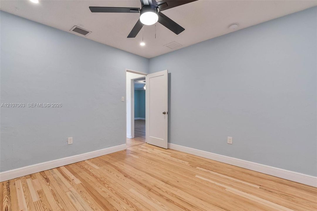 Wood-finish flooring, light blue interior paint, and a central ceiling fan with integrated lighting