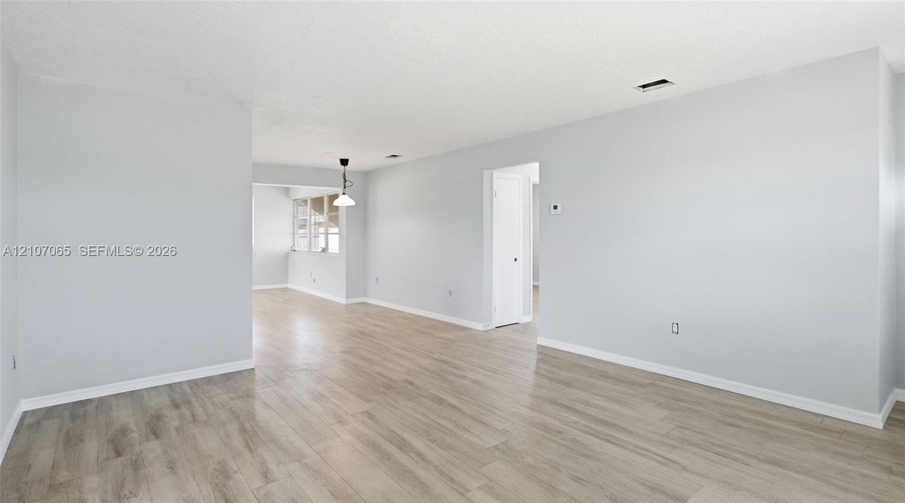 Neutral interior space featuring wood-finish flooring, light-toned wall paint, and a single-pendant ceiling fixture
