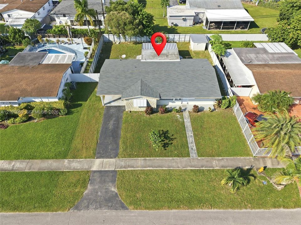 Single-story residence featuring a shingled roof, stone-veneer exterior facade, concrete driveway, and a fenced perimeter