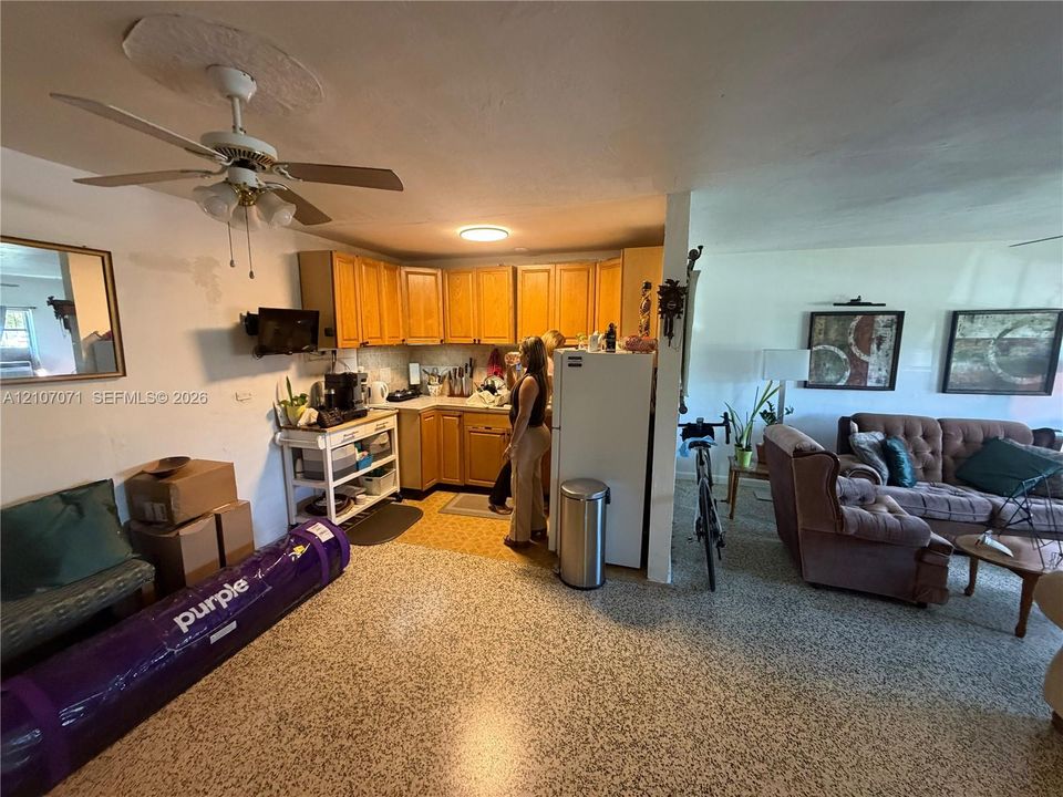Kitchen featuring wood cabinetry, solid-surface countertops, and speckled composite flooring with a ceiling-mounted light fixture and fan
