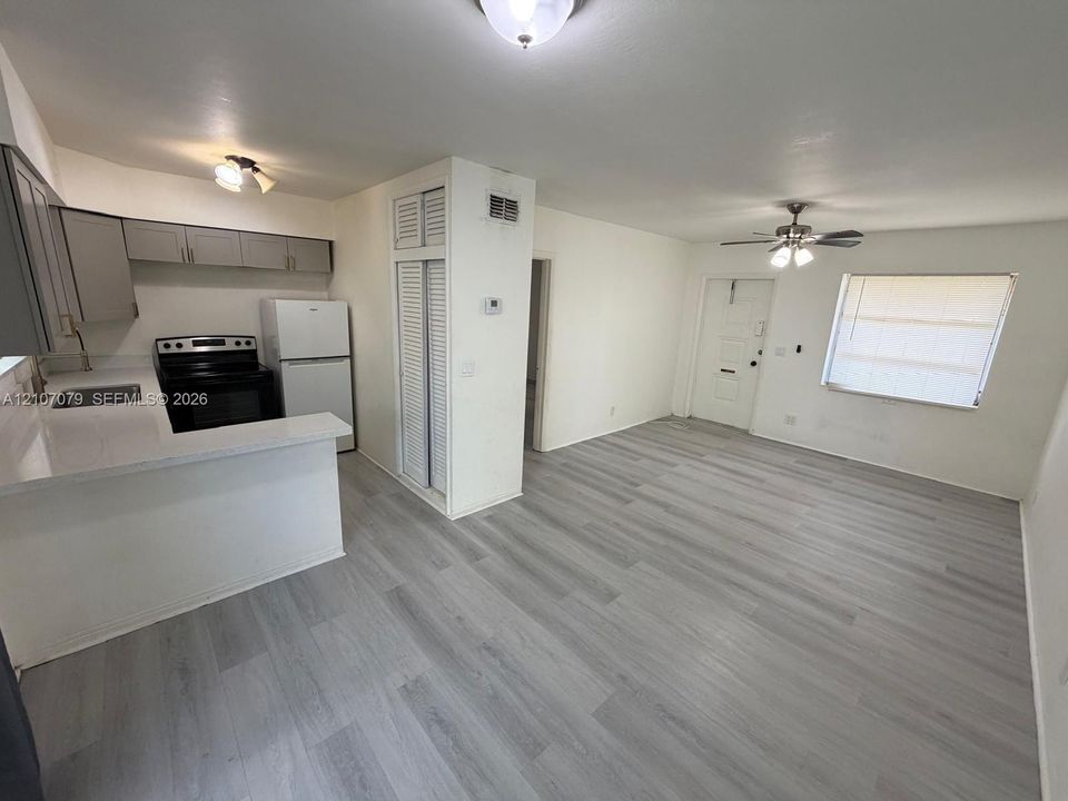 Kitchen featuring gray cabinetry, solid surface countertops, wood-finish flooring, and a ceiling fan with integrated lighting