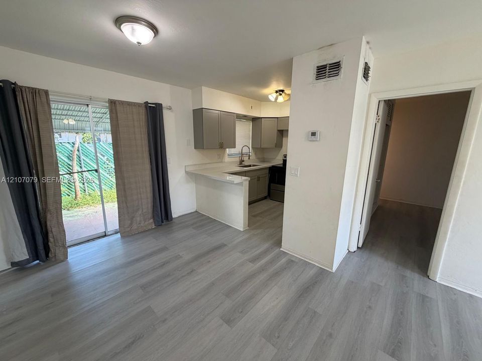 Kitchen area featuring wood-finish flooring, a breakfast bar with solid-surface countertops, grey cabinetry, and a sliding glass door