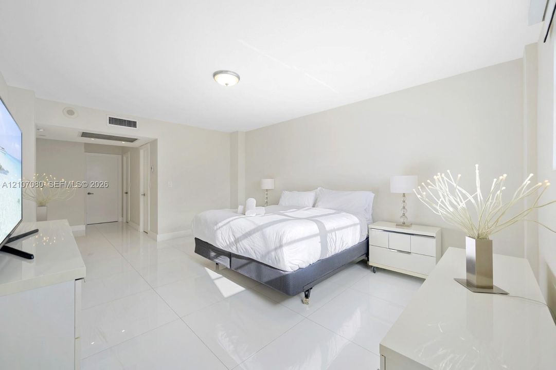 Spacious room featuring high-gloss large-format tile flooring, neutral wall finishes, recessed lighting, and integrated climate control system
