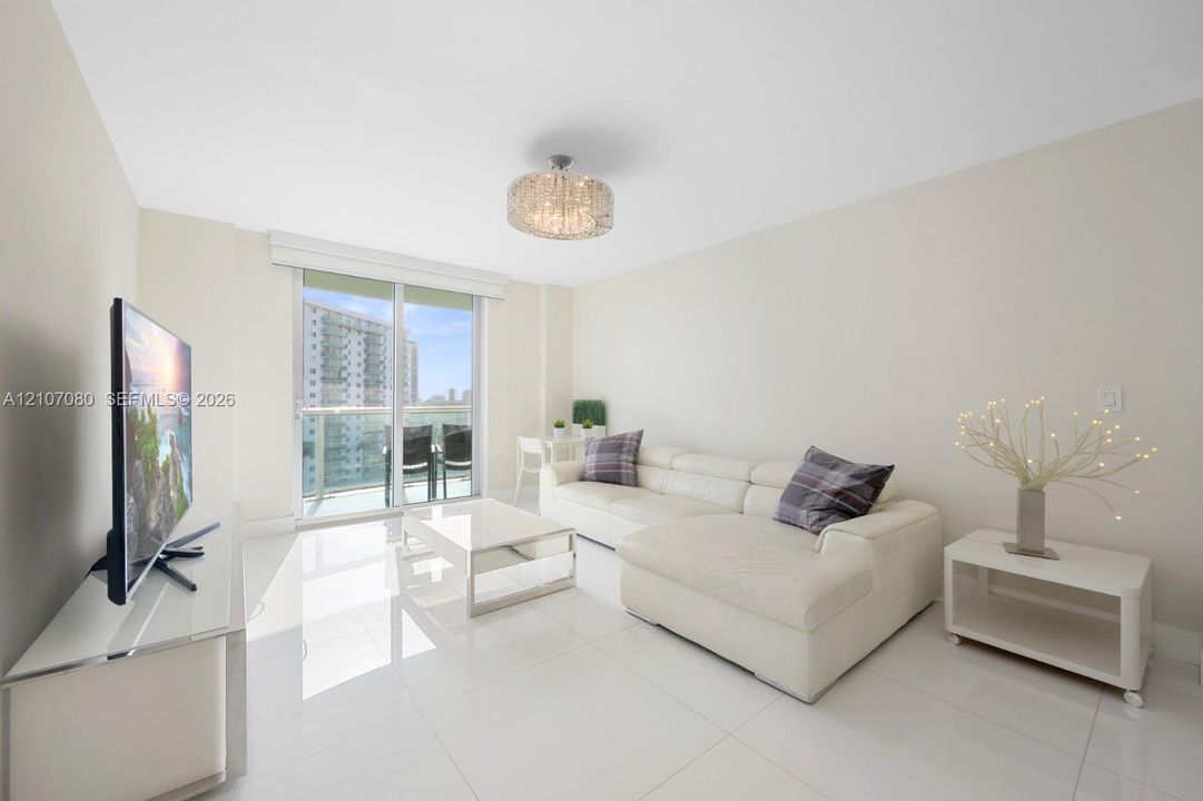 Large-format polished tile flooring, floor-to-ceiling glass sliding doors, private balcony, and decorative drum-style ceiling light fixture