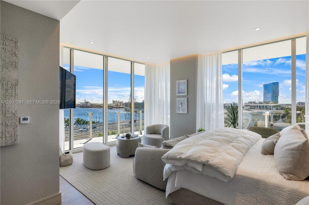 Floor-to-ceiling windows, neutral carpeting, recessed lighting, and a glass-paneled balcony