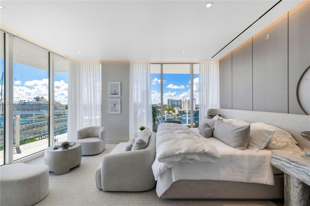 Floor-to-ceiling windows, large-format panel accent wall, recessed perimeter lighting, and neutral-tone flooring