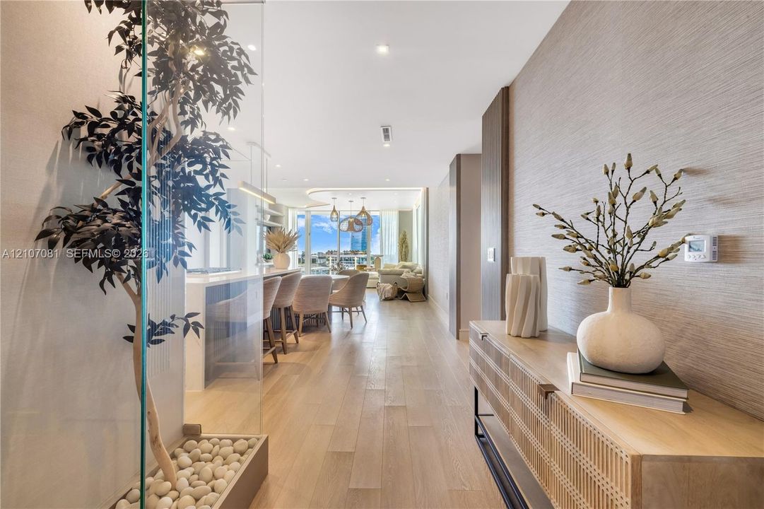 Interior featuring wood-finish flooring, textured wall coverings, recessed ceiling lighting, and a glass-enclosed decorative planter bed with stone accents