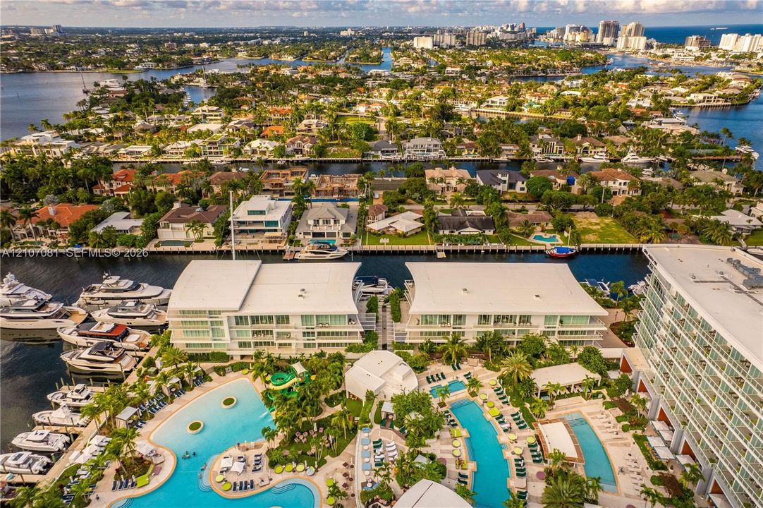 Waterfront complex featuring deep-water boat slips, multi-level swimming pools, manicured tropical landscaping, and expansive exterior balconies