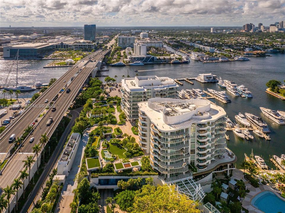 Waterfront multi-story residential building featuring wrap-around balconies, landscaped grounds, a swimming pool, and private boat slips