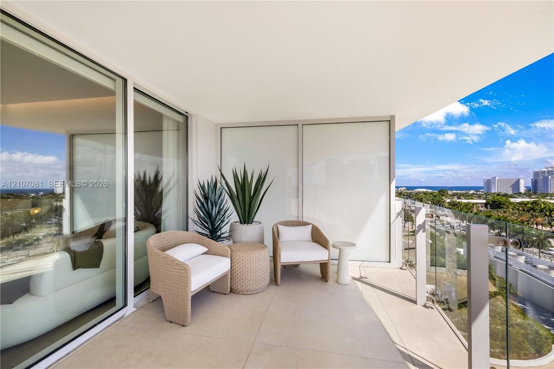 Covered balcony featuring large-format stone flooring, glass panel railings, and floor-to-ceiling sliding glass doors