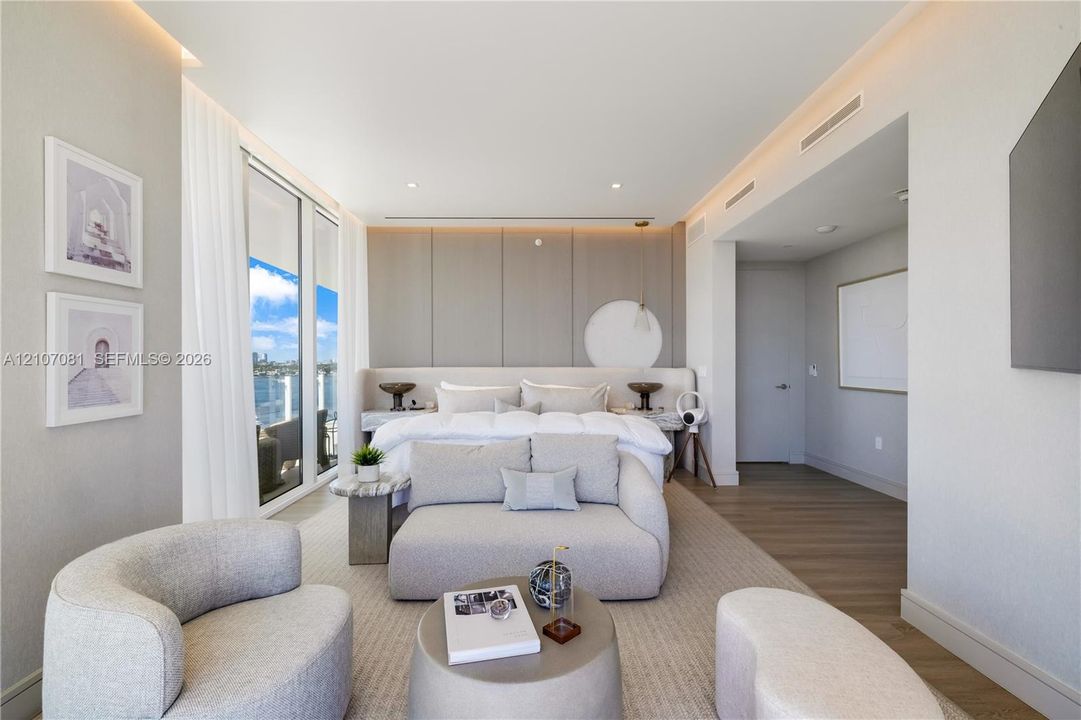 Floor-to-ceiling windows, custom paneled headboard wall with integrated lighting, wood-finish flooring, and recessed ceiling lighting
