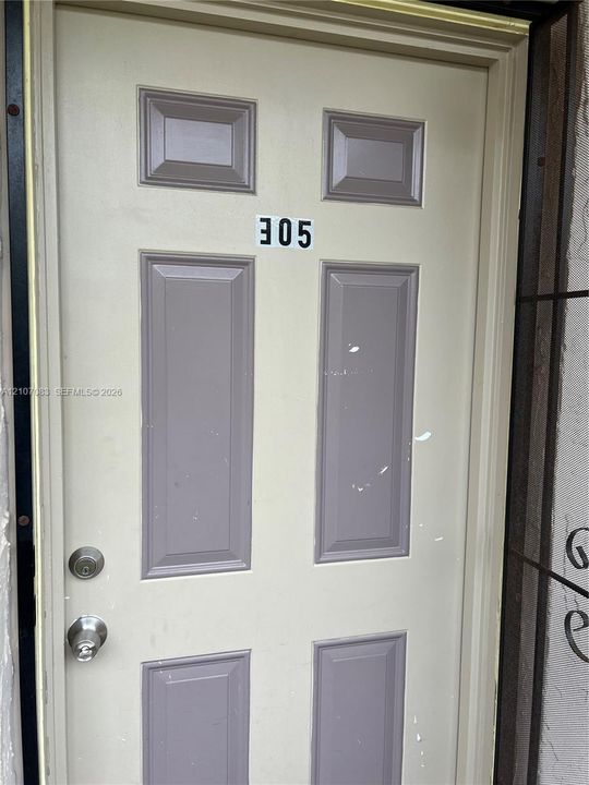 Six-panel entry door featuring metallic hardware, deadbolt lock, and metal security screen frame