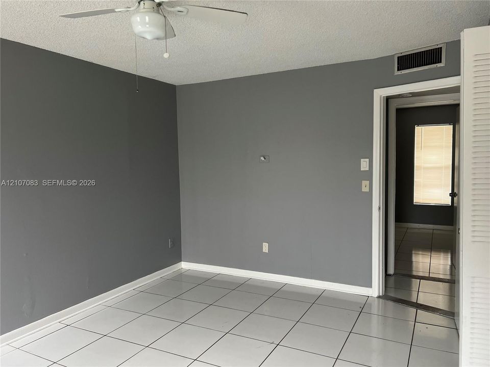 Neutral gray wall tones, white square-tile flooring, and a ceiling-mounted light fixture with integrated fan