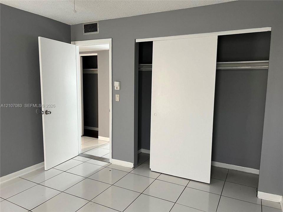 Neutral-toned interior featuring large-format ceramic tile flooring, solid-core doors, and built-in closet storage with sliding doors