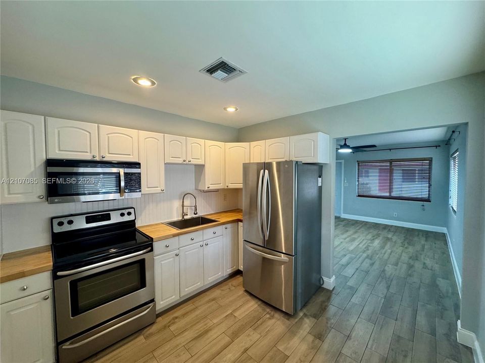 Kitchen featuring white cabinetry, wood-finish countertops, stainless steel appliances, and recessed lighting with wood-finish flooring extending into the interior space