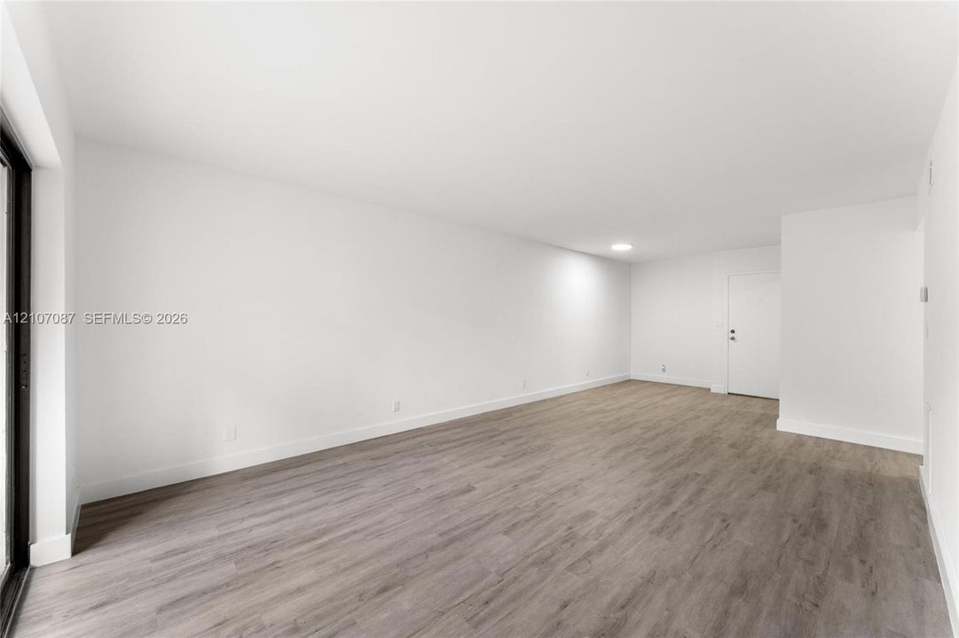 Open-concept room featuring neutral wall finishes, wood-finish flooring, recessed lighting, and a sliding glass door