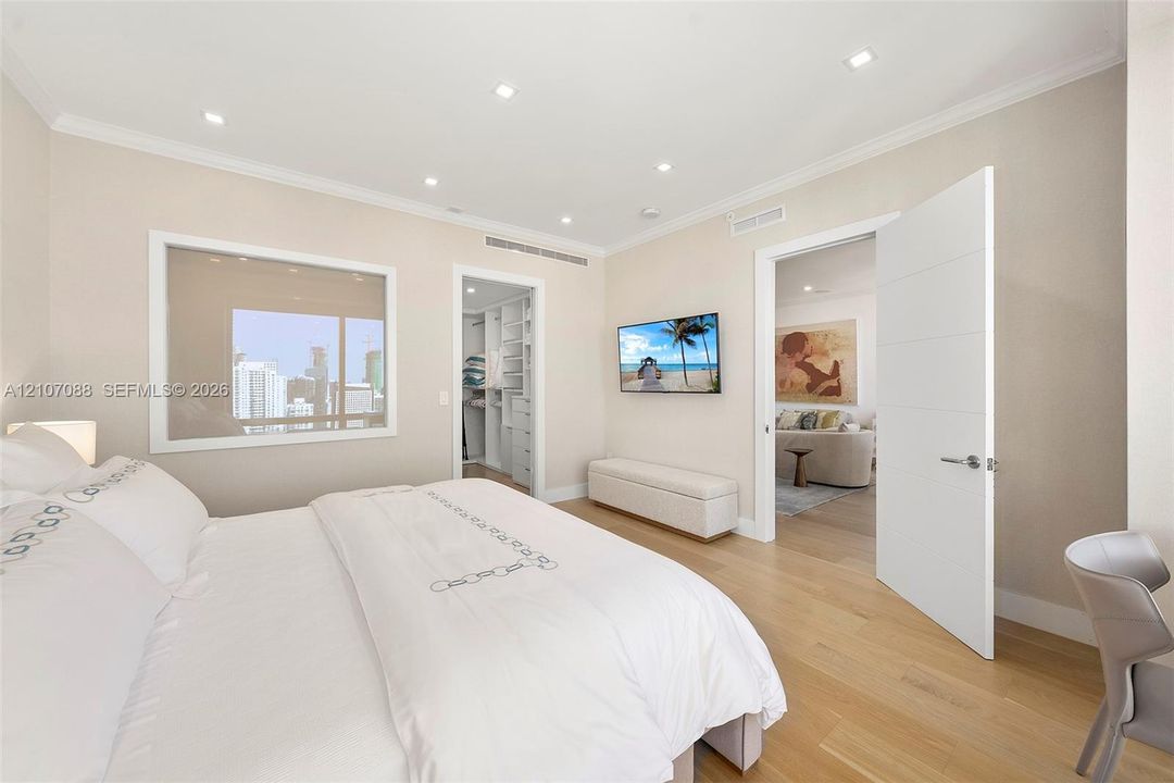 Neutral-toned interior featuring recessed lighting, wood-finish flooring, custom built-in closet cabinetry, and a large horizontal window