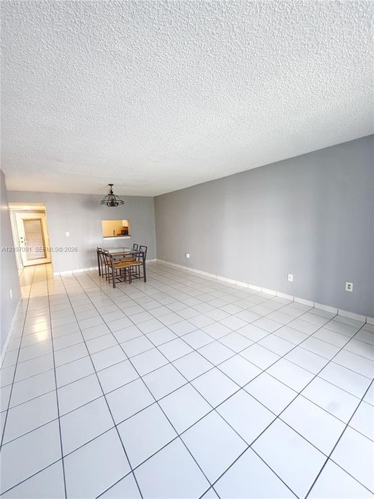 Open-concept space featuring light-colored ceramic tile flooring, neutral grey wall paint, and a pass-through opening