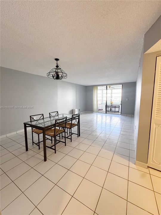 Open floor plan featuring ceramic tile flooring, a geometric metal chandelier, and a sliding glass door with access to an exterior balcony