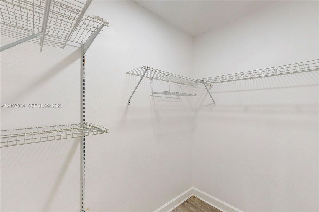 Storage area featuring wall-mounted wire shelving and wood-finish flooring