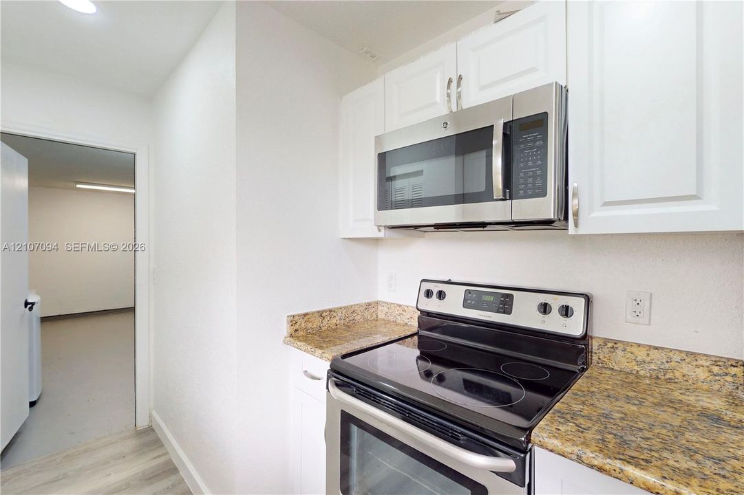 Kitchen featuring white cabinetry, stone-surface countertops, and stainless steel appliances including a built-in microwave and electric range