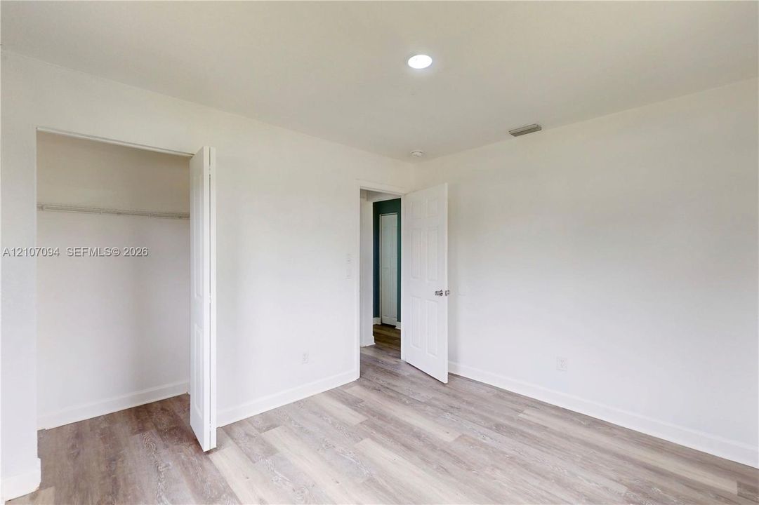 Interior space featuring wood-finish flooring, white walls, recessed ceiling lighting, and a closet with a bi-fold door