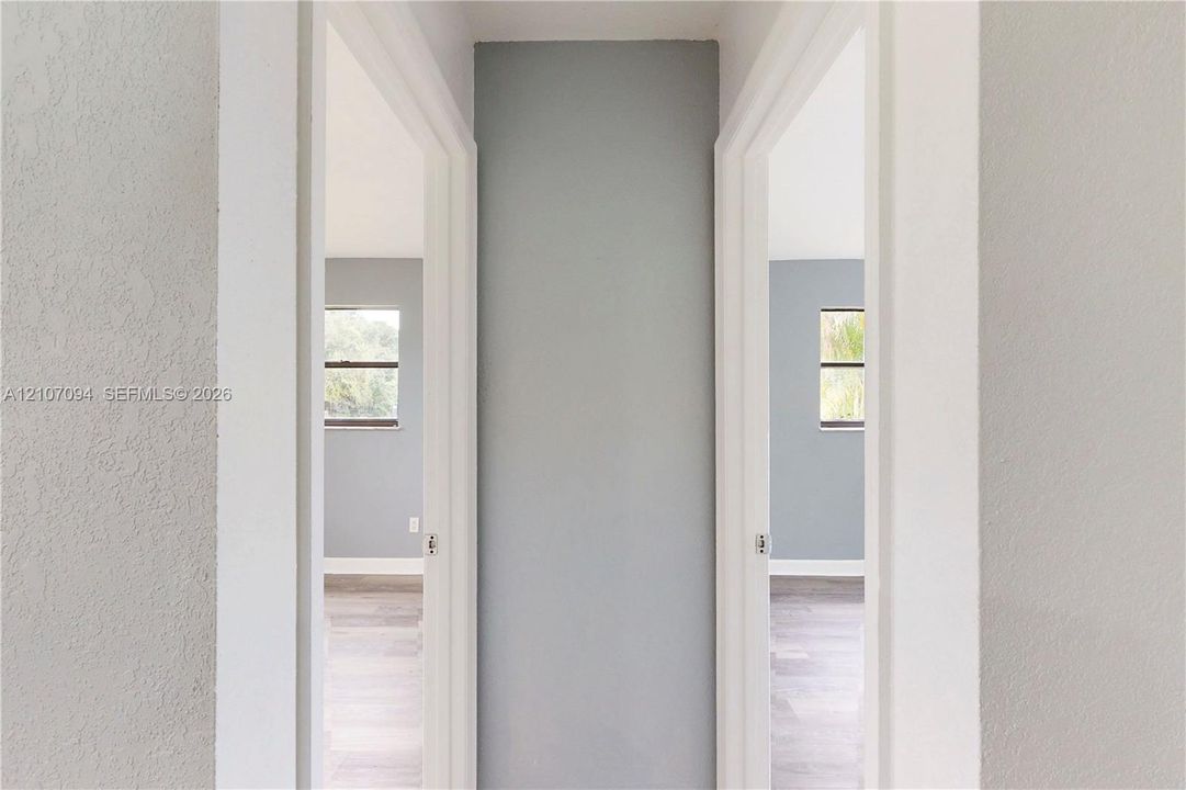 Interior hall featuring neutral-toned walls, wood-finish flooring, and two entryways with white door casings