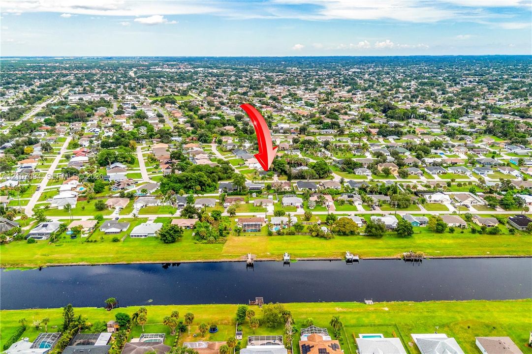 Aerial perspective featuring a residential lot with water frontage along a canal and mature landscaping