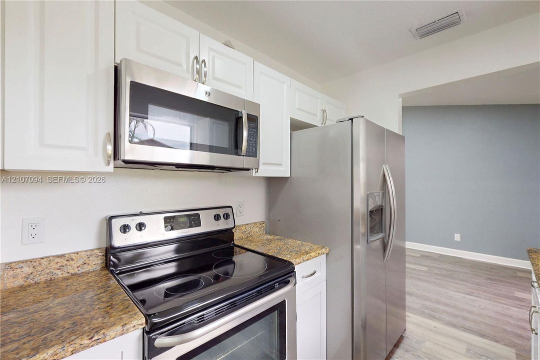 Kitchen featuring white cabinetry, stainless steel appliances, and stone-finish countertops