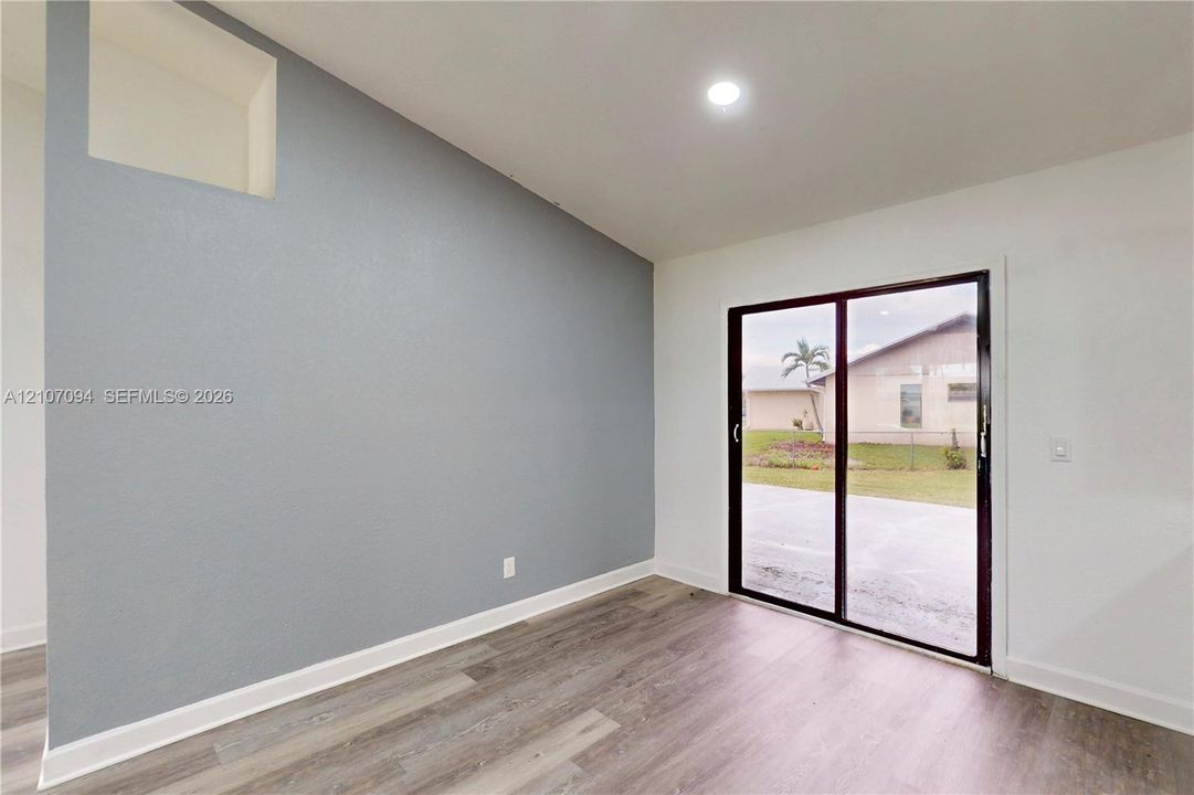 Sloped ceiling with recessed lighting, wood-finish flooring, accent wall, and sliding glass door