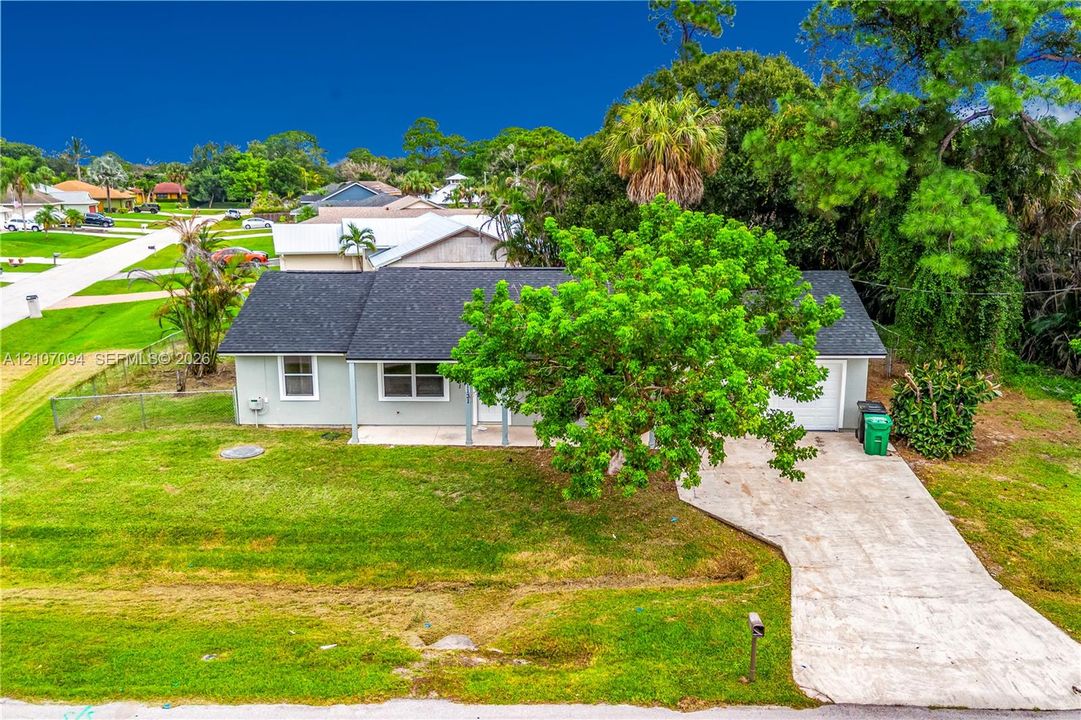 Single-story residence featuring a light-toned exterior, shingled roof, concrete driveway, and covered front entry