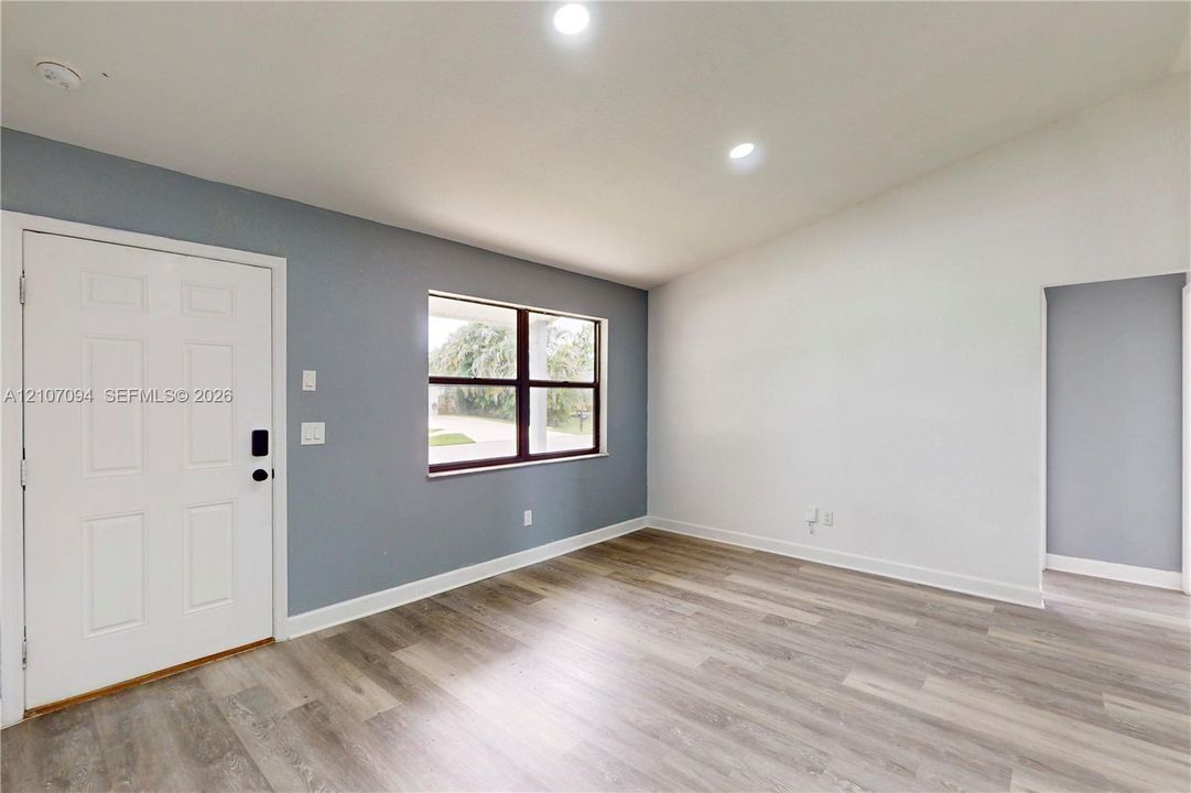 Vaulted ceilings, wood-finish flooring, recessed lighting, and a multi-pane window