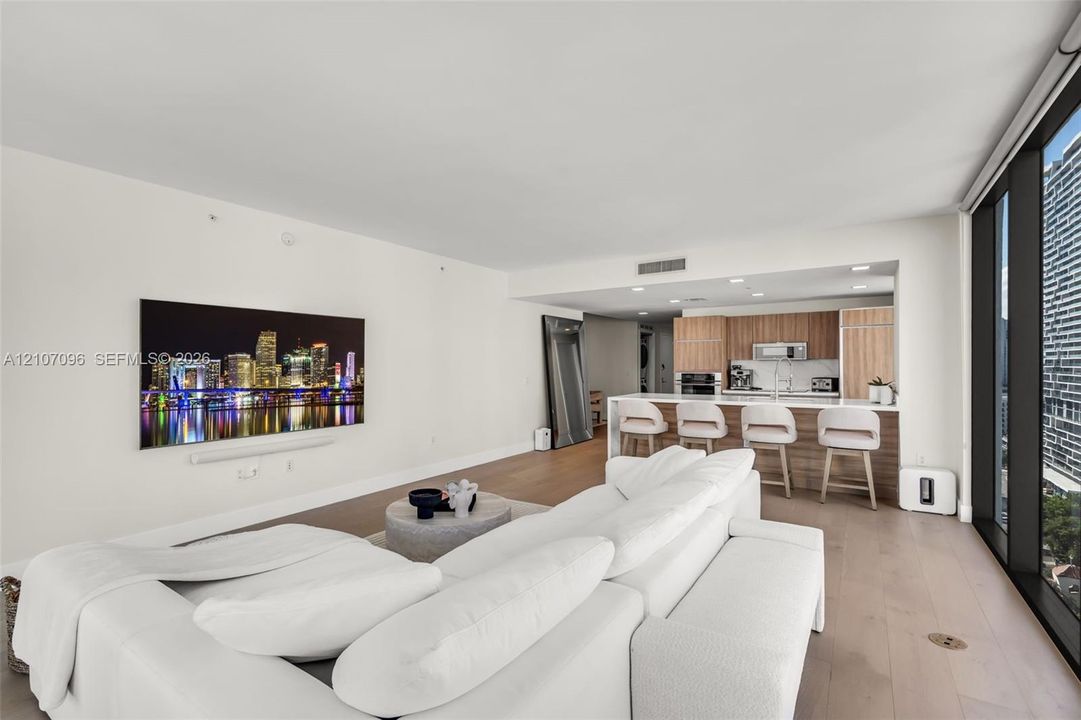 Open-concept living space with wood-finish flooring, floor-to-ceiling windows, and recessed lighting