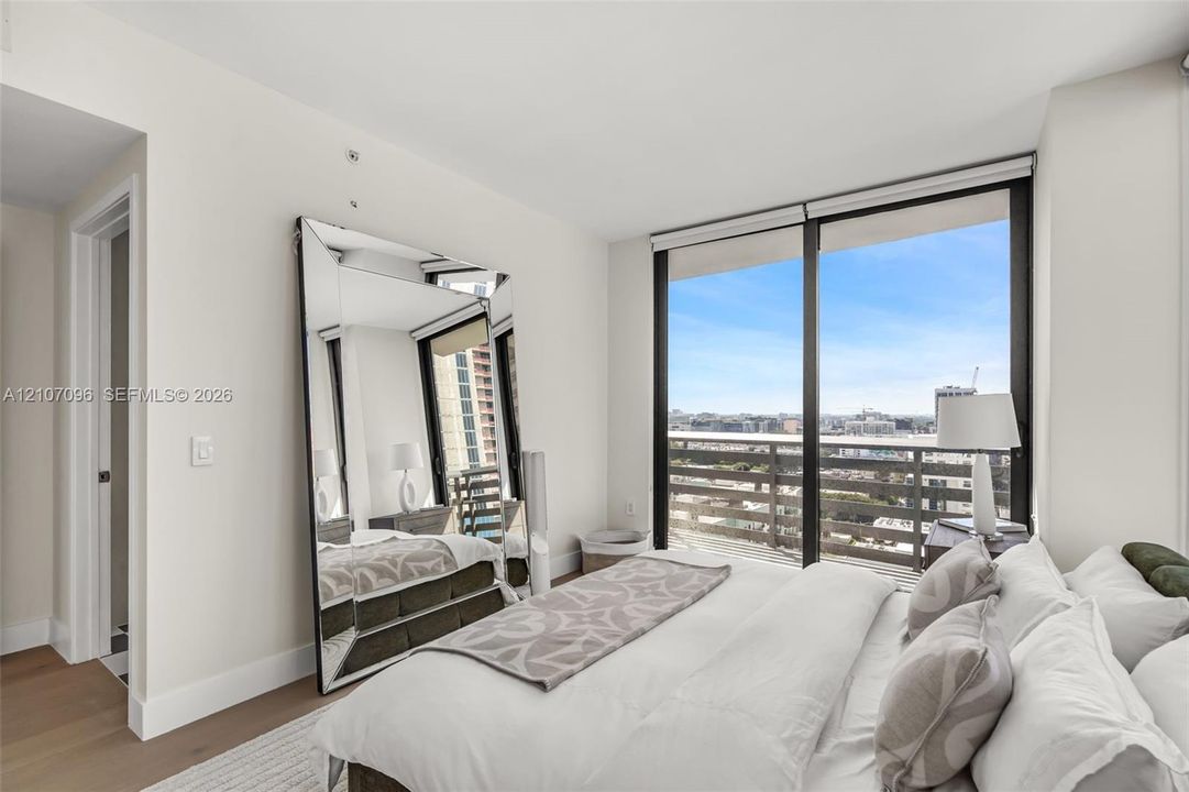 Floor-to-ceiling windows, wood-finish flooring, and private balcony with metal railing