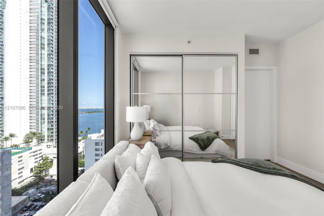 Floor-to-ceiling windows, mirrored sliding-door closet, and neutral interior finishes