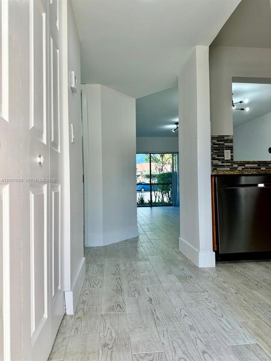 Wood-finish flooring throughout, stainless steel dishwasher, mosaic tile backsplash, and floor-to-ceiling glass sliding door