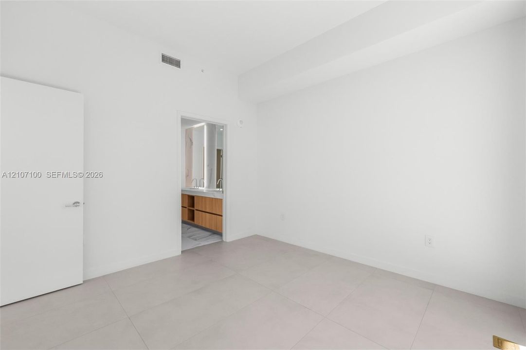 Minimalist interior featuring large-format ceramic tile flooring, smooth wall finish, and a solid-core interior door