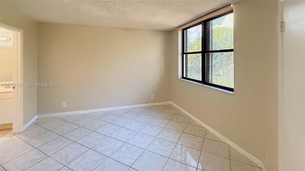 Interior room featuring large-format ceramic tile flooring, neutral wall paint, and a multi-pane window with black framing