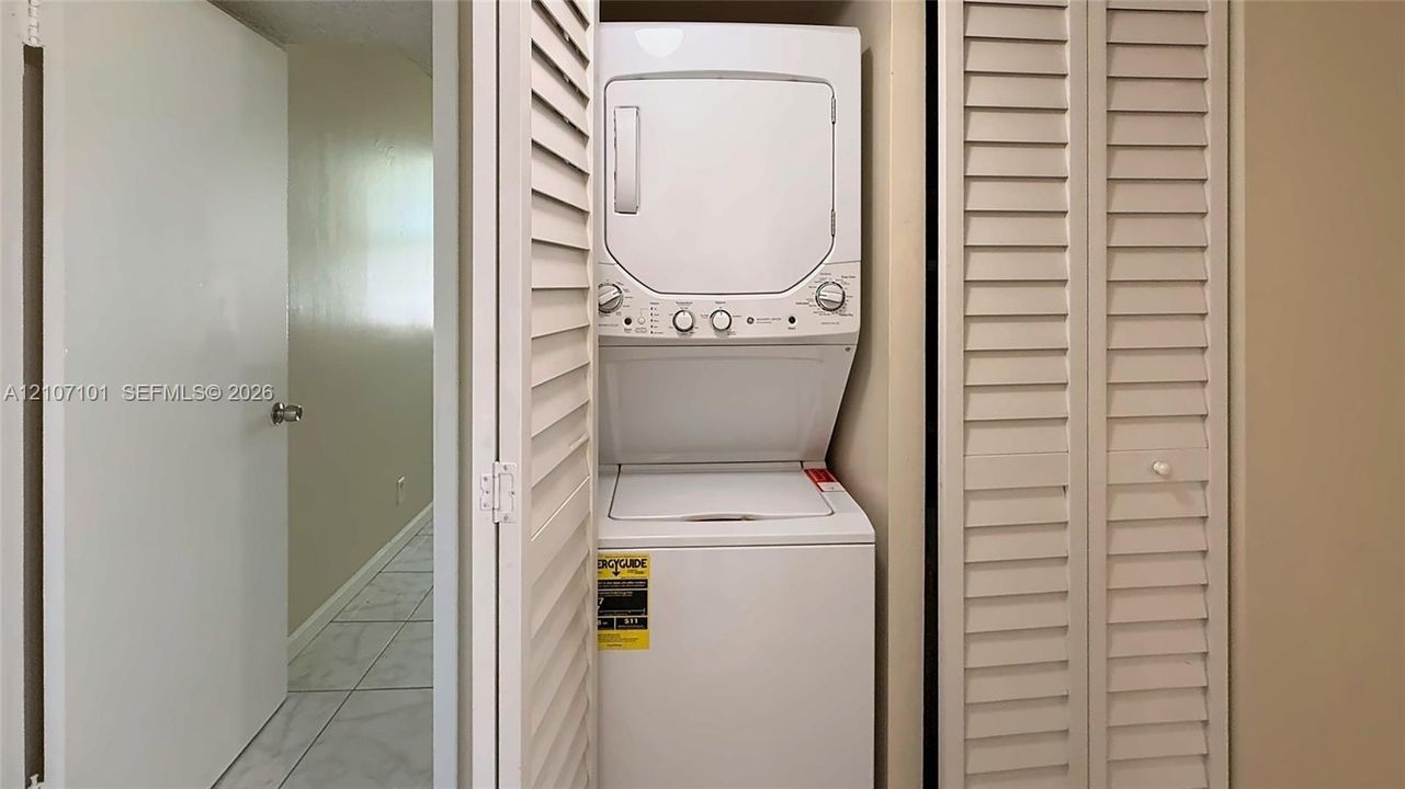 Stackable laundry unit housed within a closet featuring dual louvered doors