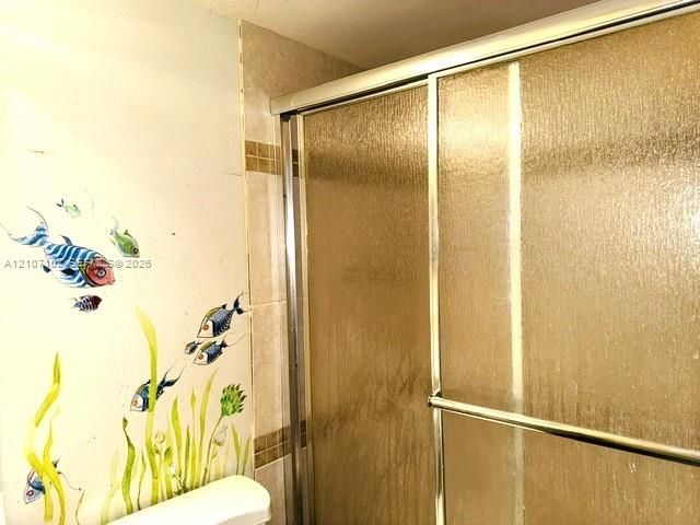 Guest Bathroom Includes Shower enclosure featuring textured glass sliding doors and ceramic wall tiling with integrated decorative accent banding