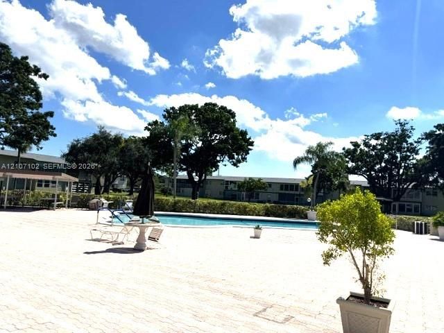 Swimming pool with masonry deck, surrounded by mature trees and landscaped shrubbery
