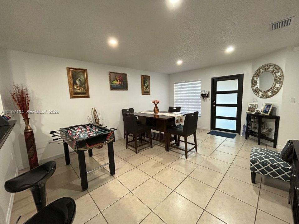 Neutral-toned tile flooring, recessed ceiling lighting, and a modern entry door featuring four horizontal frosted glass panels