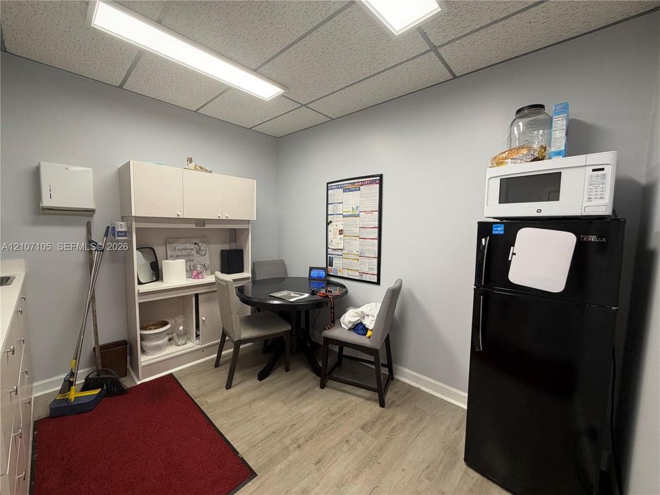 Room featuring wood-finish flooring, a built-in storage hutch, and a suspended drop ceiling with rectangular LED lighting