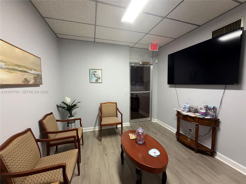 Wood-finish flooring, drop ceiling with integrated lighting, and glass-paneled entry door
