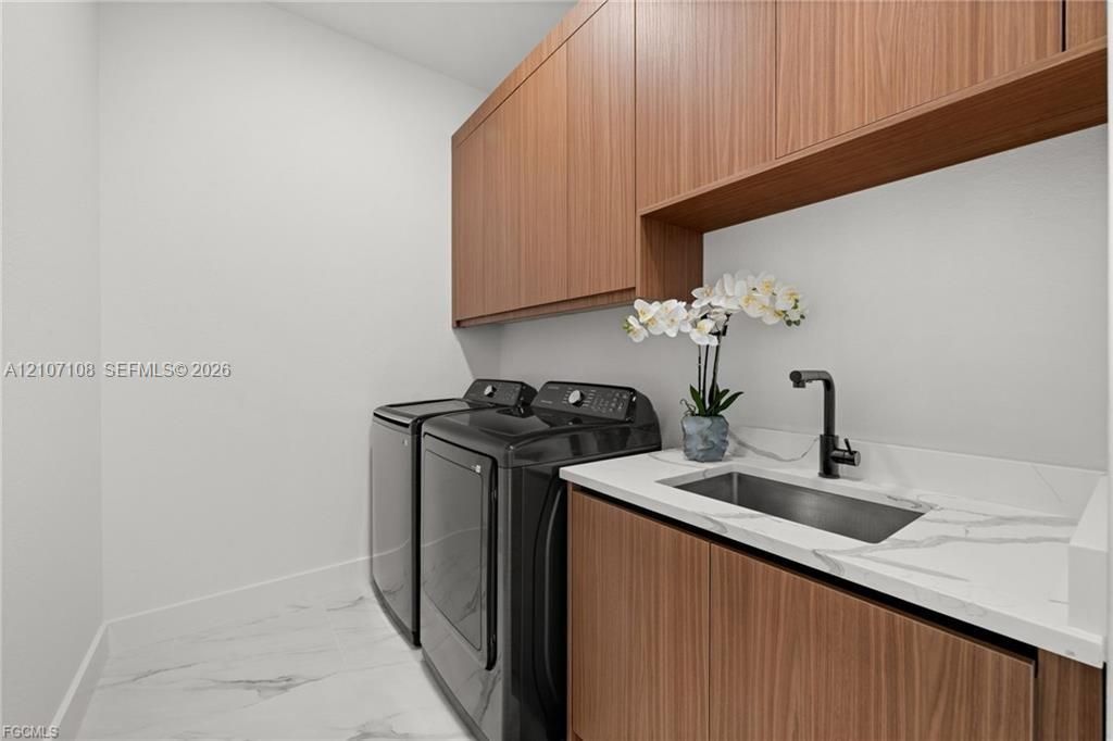Custom wood-finish cabinetry, white stone-look countertop, integrated stainless steel sink, matte black gooseneck faucet, and white large-format flooring