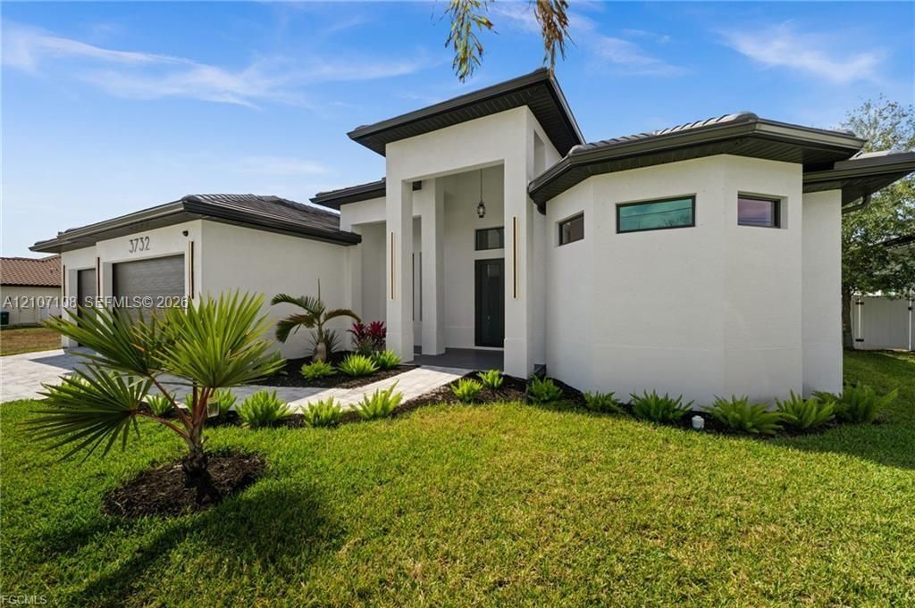 Modern exterior featuring a smooth stucco facade, high-contrast dark roofing, geometric architectural lines, a covered recessed entryway, and a paved driveway